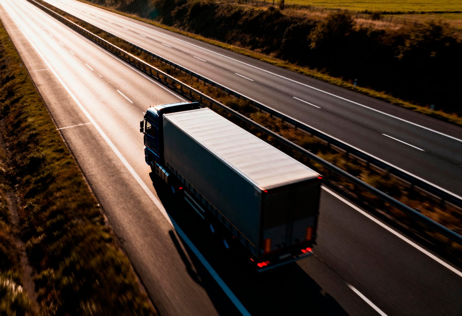 camion-semi-remolque-de-larga-distancia-conduciendo-en-una-autopista-de-varios-carriles-al-atardecer